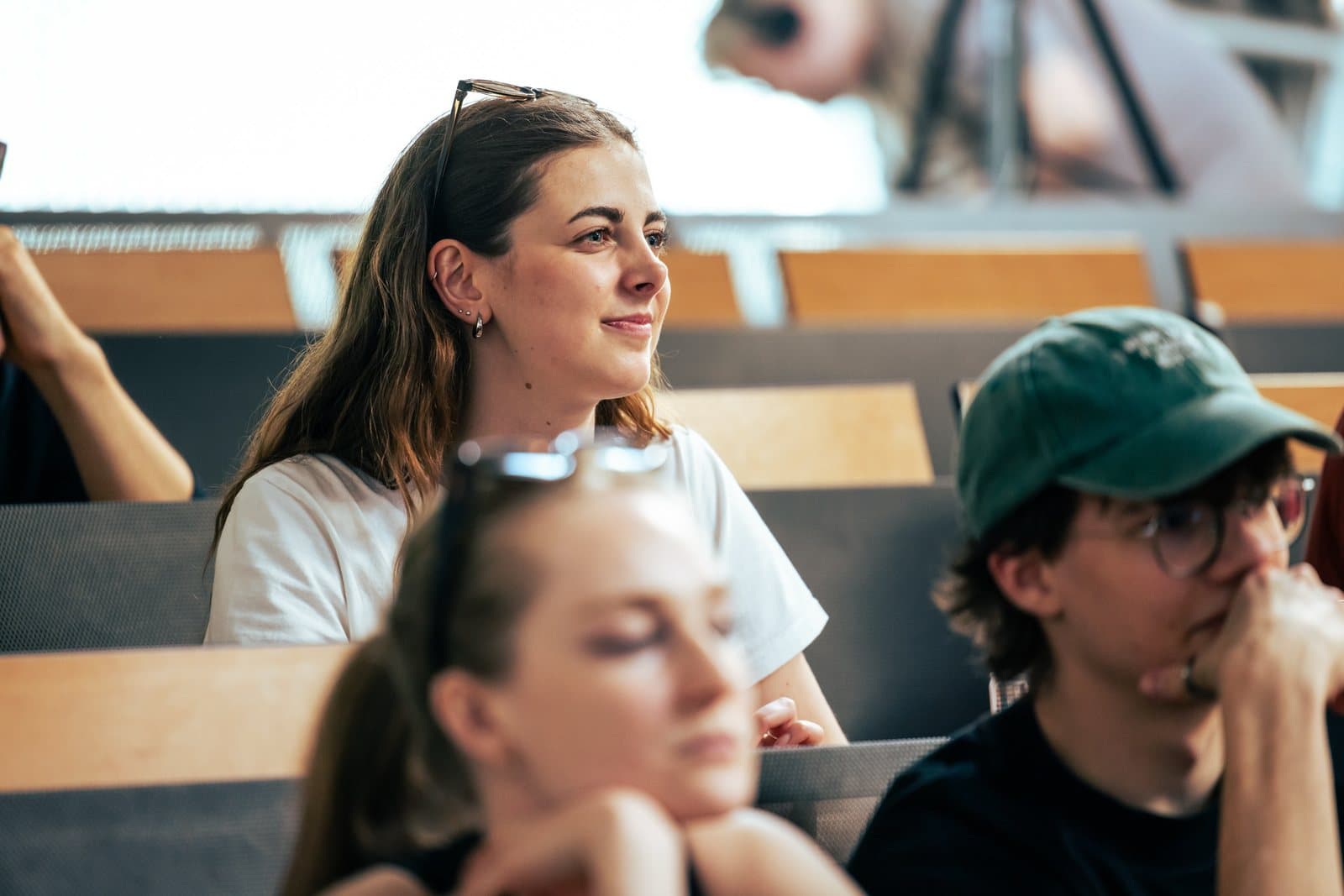 Studentka v publiku DIALOQ se usmívá během rozhovoru
